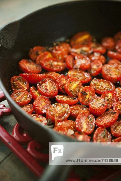 Halved Cherry Tomatoes Cooked with Salt  Pepper and Rosemary in a Skillet