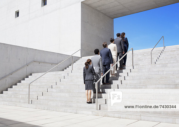 Geschäftsleute  die in einer Reihe auf einer Stadttreppe stehen.