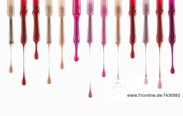 Close up of multicolor fingernail polish dripping from brushes