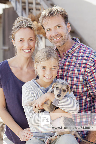 Portrait of smiling family holding puppy
