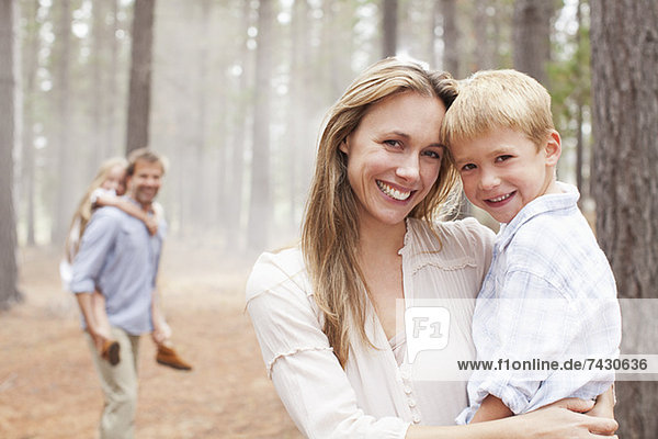 Porträt der lächelnden Mutter mit Sohn im Wald