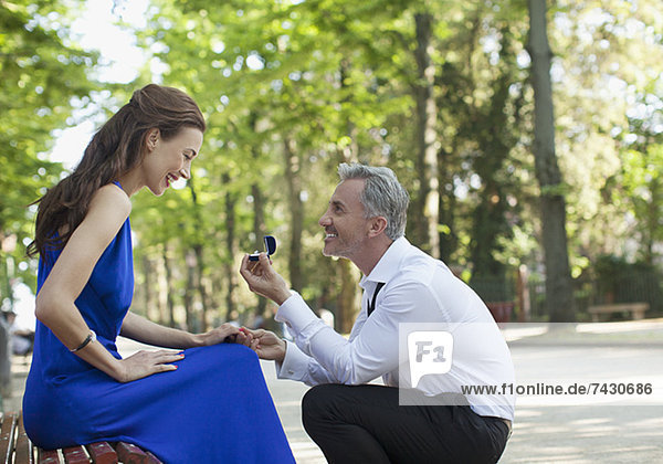Mann mit Verlobungsring,  der seiner Freundin im Park einen Antrag macht.