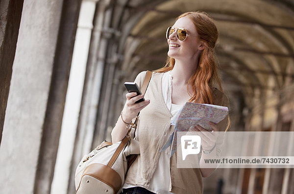 Lächelnde Frau mit Handy und Karte im Flur