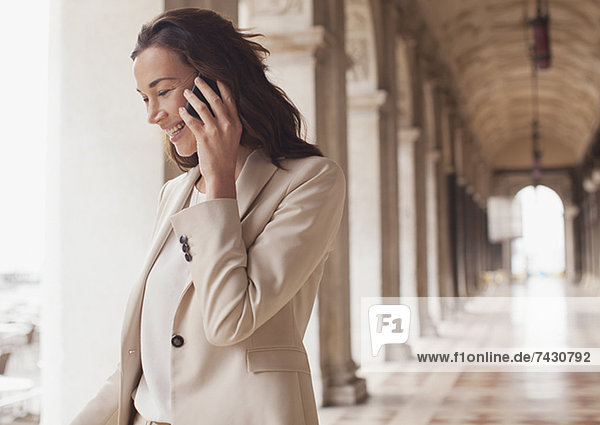 Lächelnde Geschäftsfrau beim Telefonieren im Flur