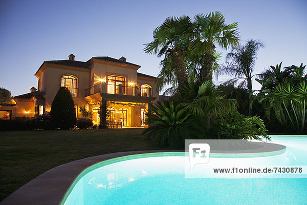 Luxus-Schwimmbad und Villa bei Nacht beleuchtet