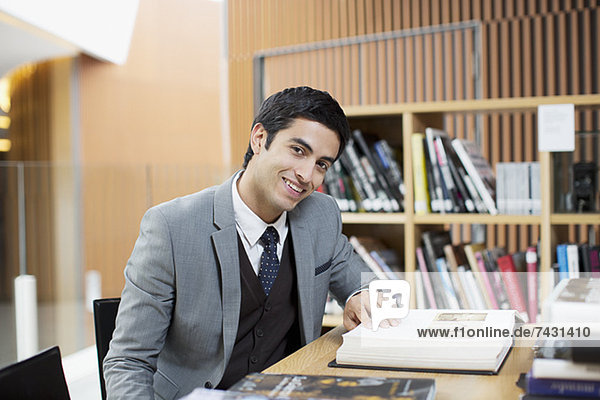 Porträt des lächelnden Geschäftsmannes beim Lesen in der Bibliothek