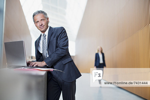 Portrait of confident businessman using laptop in office