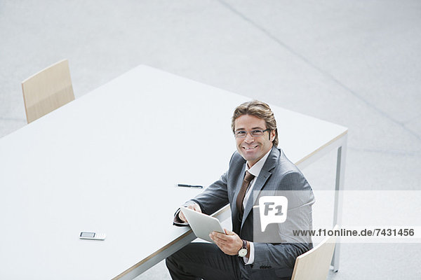 Porträt eines selbstbewussten Geschäftsmannes mit digitalem Tablett am Tisch