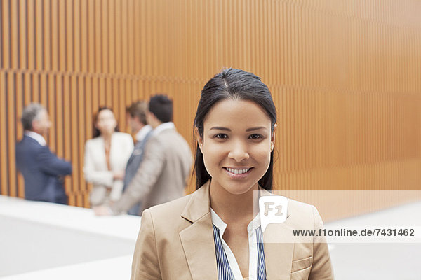 Portrait of smiling businesswoman with co-workers meeting in background
