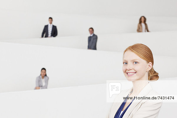 Porträt einer lächelnden Geschäftsfrau mit Mitarbeitern auf der Treppe im Hintergrund