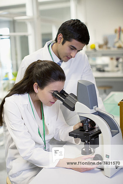 Scientists using microscope in laboratory