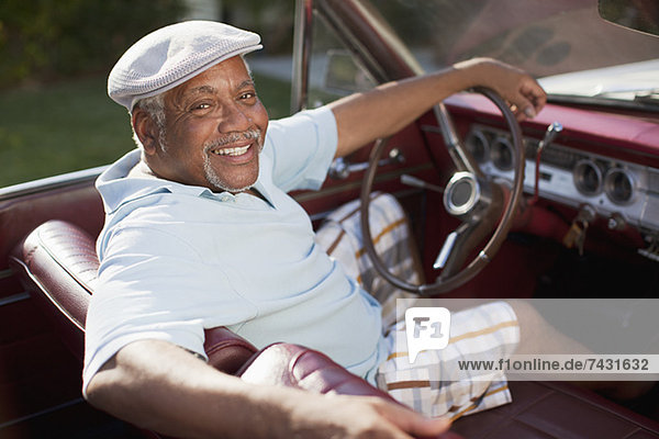 Smiling older man driving convertible