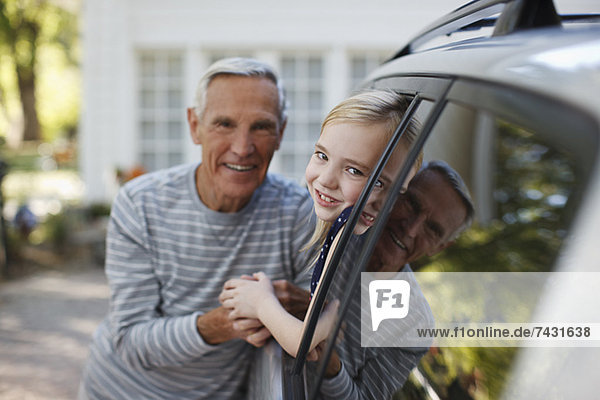 Älterer Mann im Gespräch mit Enkelin im Autofenster