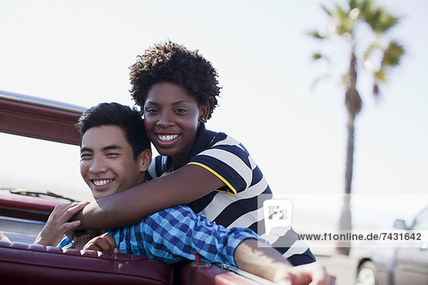 Smiling couple hugging in convertible