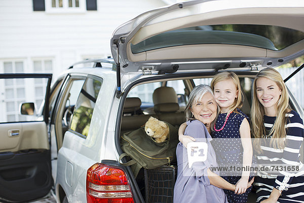 Drei Generationen von Frauen sitzen im Kofferraum