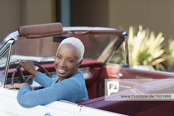 Lächelnde ältere Frau beim Cabriofahren