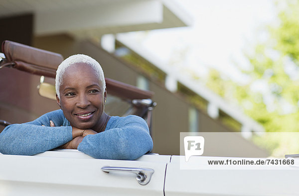 Lächelnde ältere Frau im Cabrio sitzend