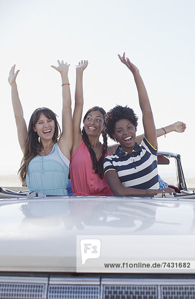 Lächelnde Frauen jubeln im Cabriolet