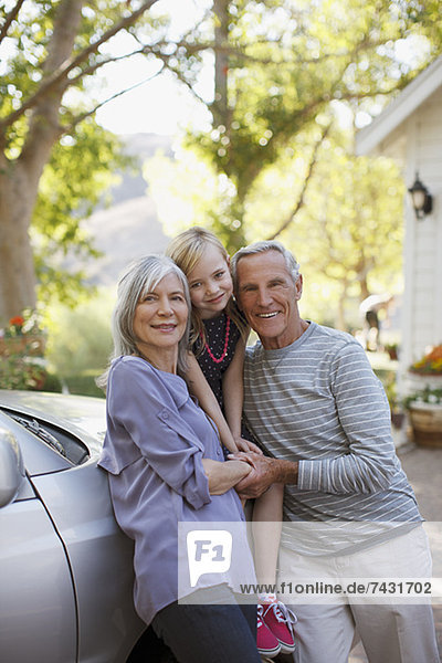Älteres Ehepaar und Enkelin  die sich auf das Auto stützen
