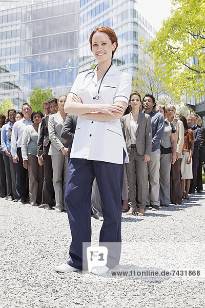 Porträt einer selbstbewussten Krankenschwester mit Geschäftsleuten im Hintergrund