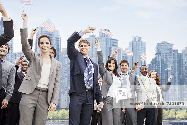 Portrait of smiling business people waving American flags