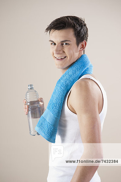 junger lächelnder Mann mit einer Wasserflasche