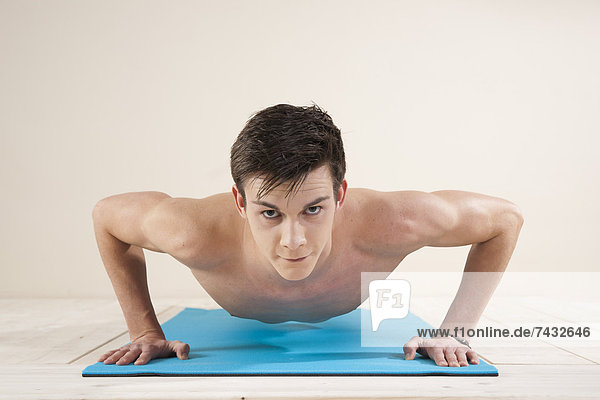 young man doing push ups on a gymnastics mat