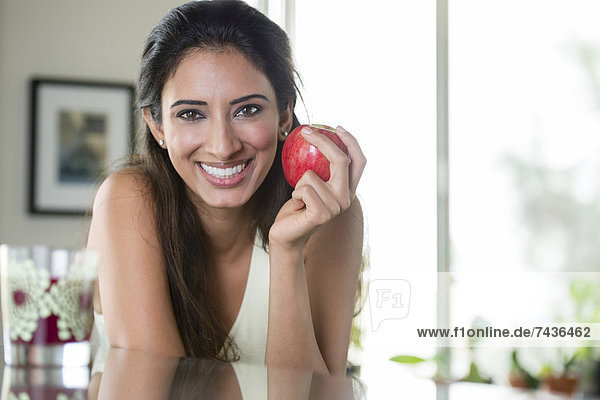 Indian woman holding apple in kitchen