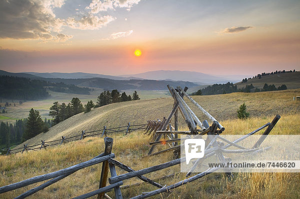 Sunset over the mountains and valleys of Montana  Strong wooden stock fencing on grasslands