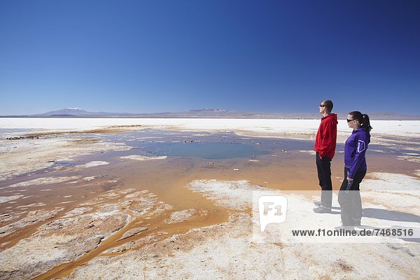 Couple standing next to geyser on Salar de Uyuni (Salt Flats of Uyuni)  Potosi Department  Bolivia  South America