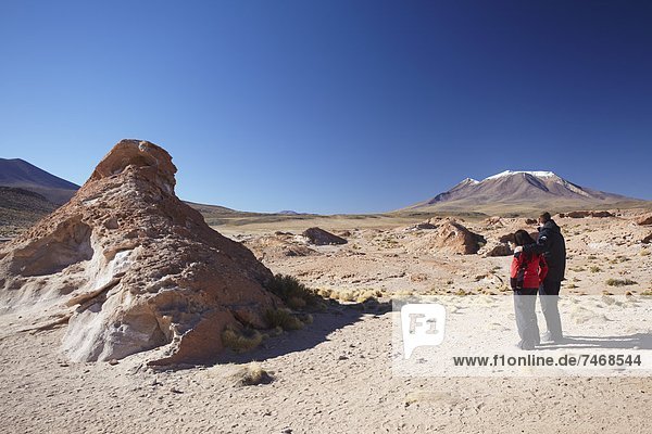Couple looking at volcano on Altiplano  Potosi Department  Bolivia  South America