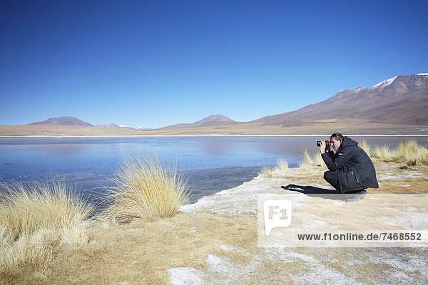 Man taking photos at Laguna Canapa on Altiplano  Potosi Department  Bolivia  South America