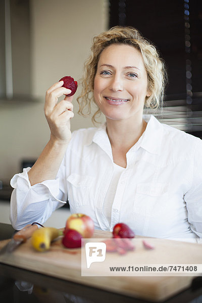 Frau isst Obst in der Küche