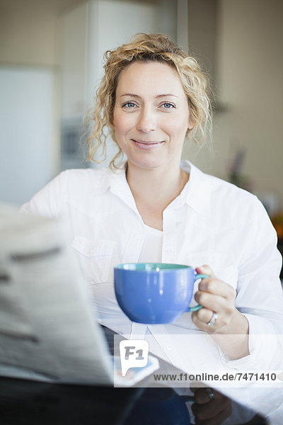 Frau trinkt Kaffee und liest Papier