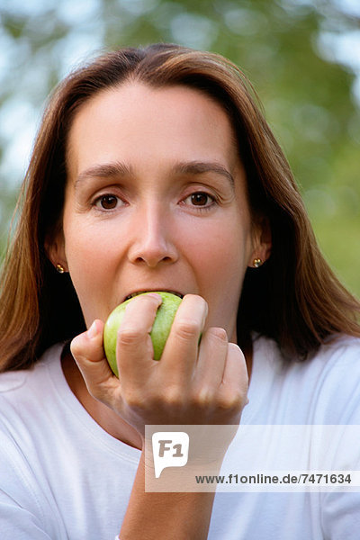 Frau isst Apfel im Freien