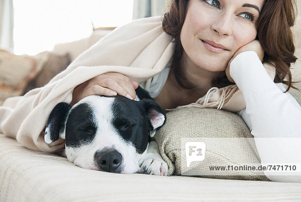 Frau entspannt auf Sofa mit Hund