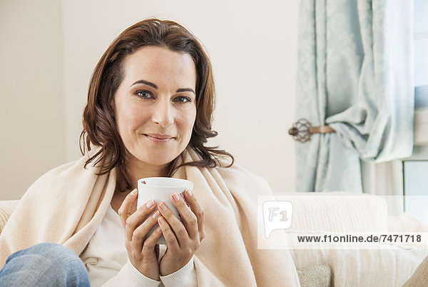Frau bei einer Tasse Kaffee auf dem Sofa