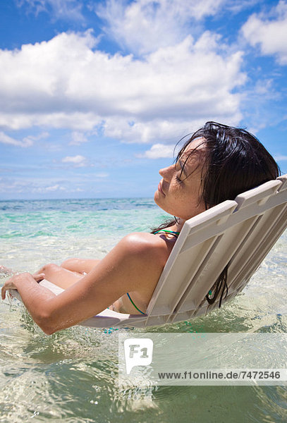 Woman in lawn chair in tropical water