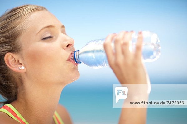 Woman drinking water bottle outdoors