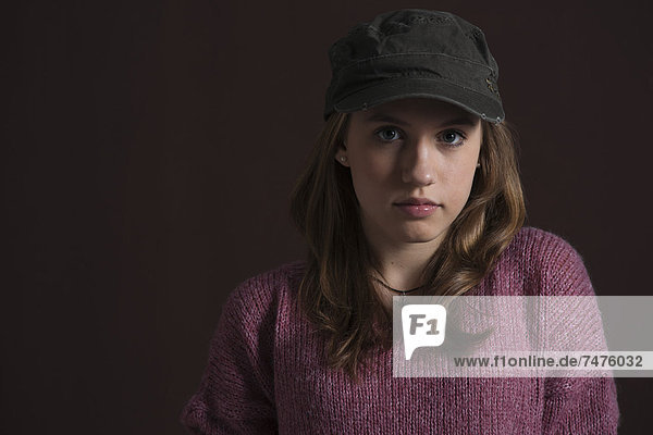 Close-up Portrait of Blond  Teenage Girl wearing Baseball Hat  Studio Shot on Black Background