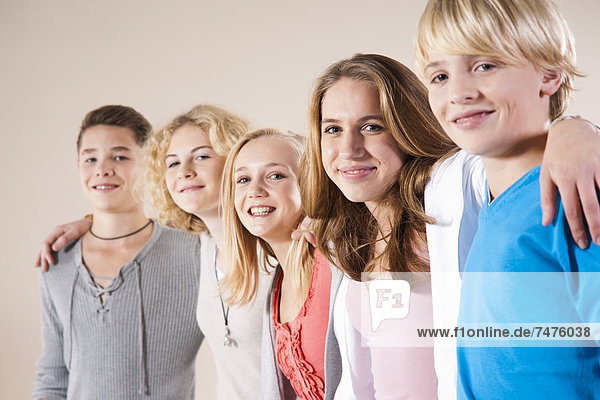 Portrait of Group of Teenage Boys and Girls  Standing in a Row with Arms around Shoulders  Studio Shot on White Background