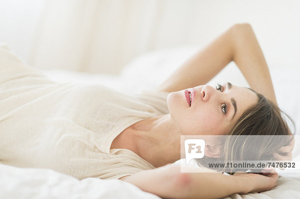Portrait einer jungen Frau im Bett liegend