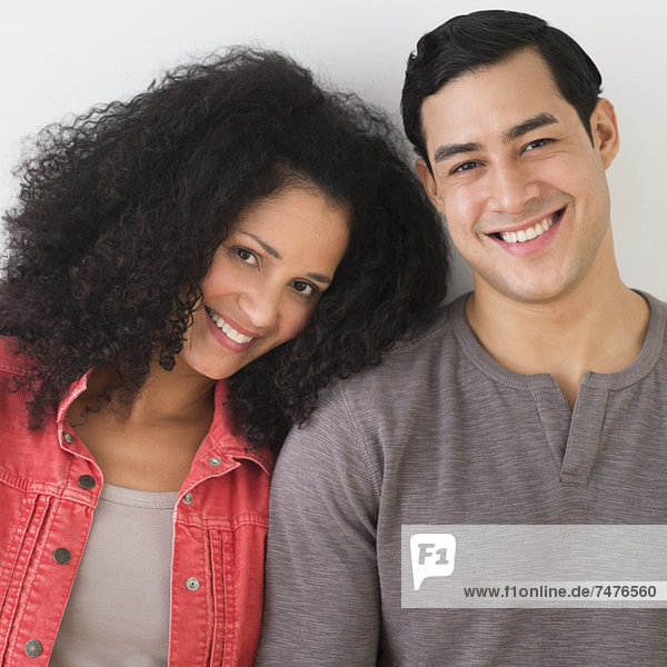 Portrait of smiling couple standing against white wall