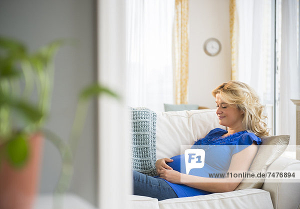 Schwangere Frau sitzt auf sofa