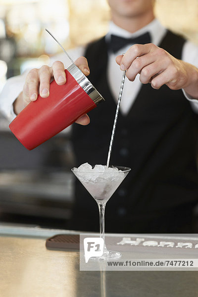 Young bartender pouring cocktail