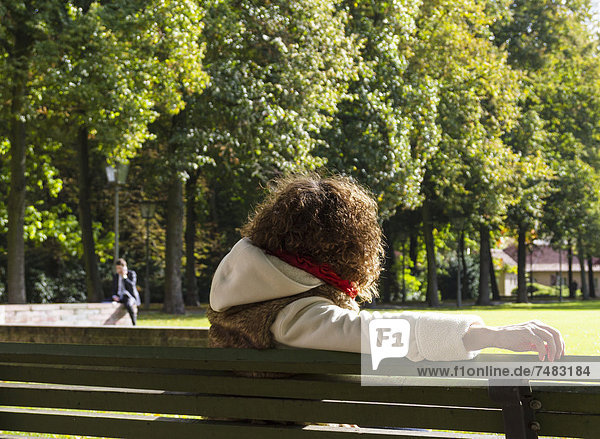 Young woman sitting on a bench watching a man speaking on the phone Berlin Germany Europe