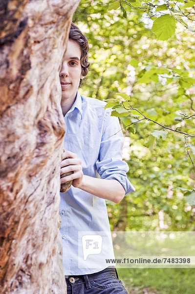 Junger Mann steht an einem Baum im Wald  Schweden  Europa