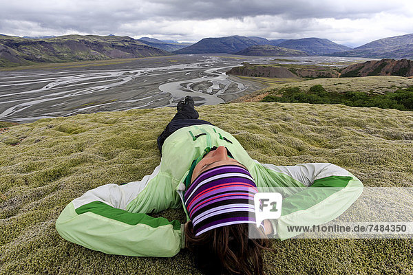 Young woman lying in a moss landscape  Sandur of Vatnajoekull  Iceland  Europe
