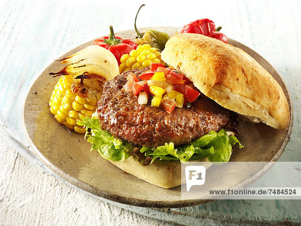 Barbecue Beef Burger  Hamburger  in einem Ciabatta-Br÷tchen mit Salsa and R÷stgemüste auf einem rustikalen Teller