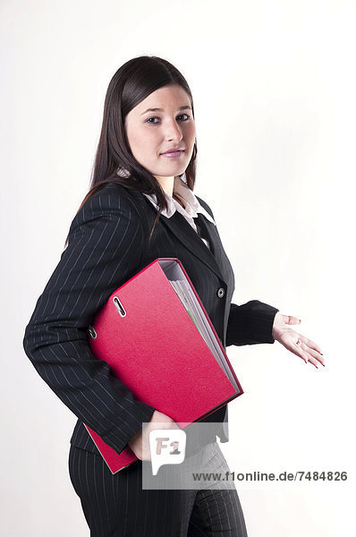 Geschäftsfrau mit rotem Aktenordner unter dem Arm in fragender Haltung